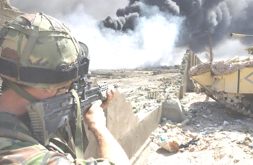 A soldier serving with Number 1 Company 1st Battalion, The Irish Guards, looks for possible Iraqi enemy positions, as Royal Engineer technicians prepare to cap one of the burning oil wells within the city of Basra.